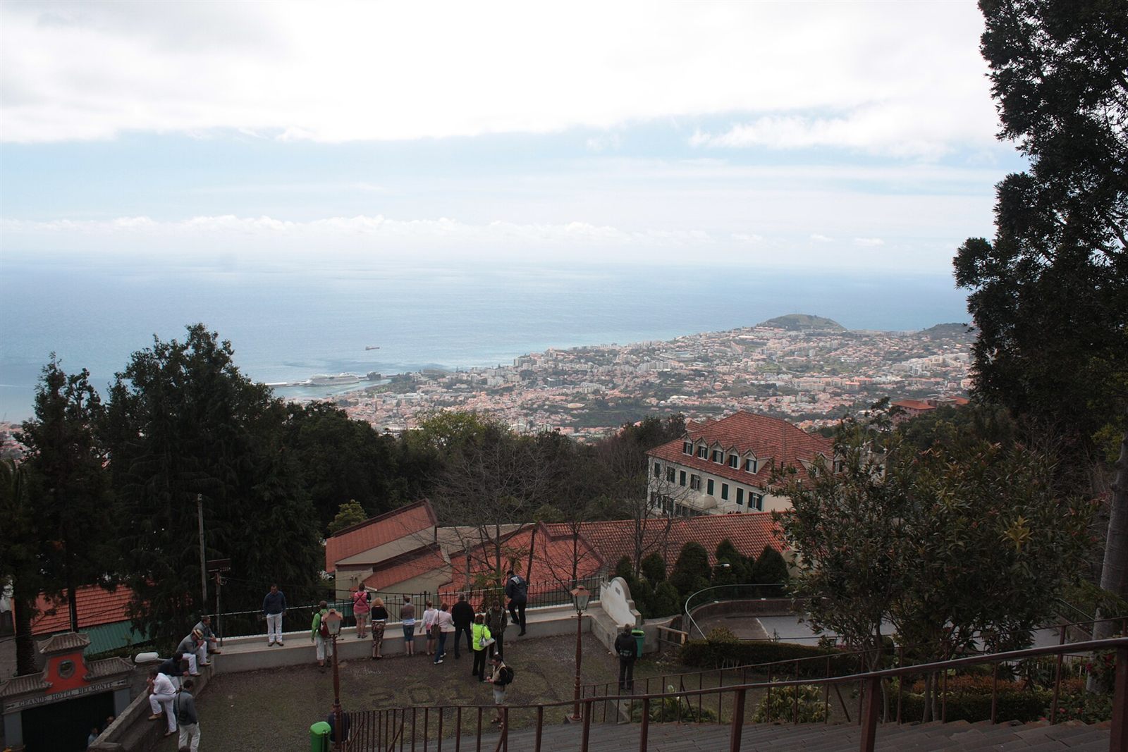 Viewpoint terrace at Monte with tourists overlooking red-roofed houses of Funchal and the coastline below