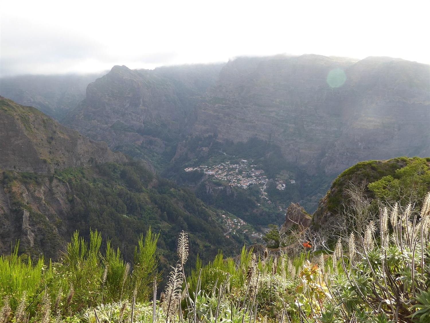 Deep valley in Madeira's interior with a small village set among steep, cloud-veiled cliffs