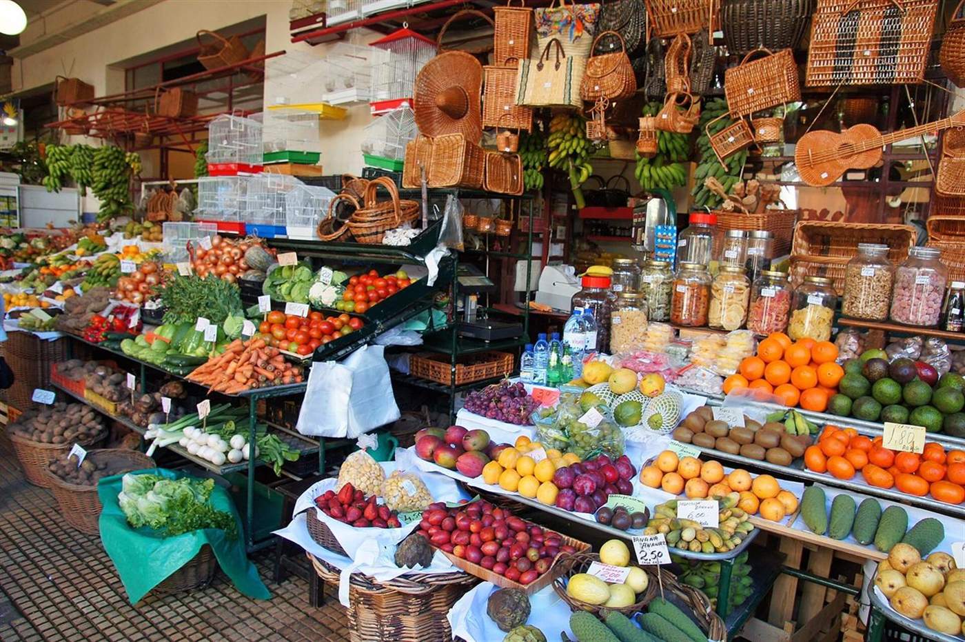 Fruit and vegetable stall with woven baskets overhead at Mercado dos Lavradores, Funchal, Madeira