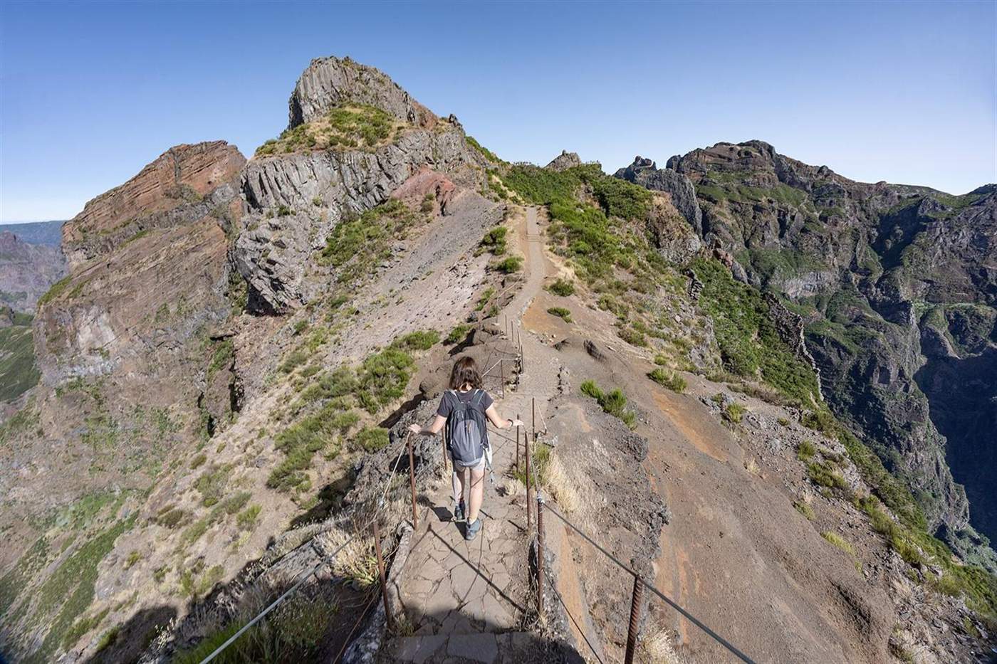 Hiker on the narrow stone ridge path of Vereda do Areeiro between Pico do Arieiro and Pico Ruivo, Madeira