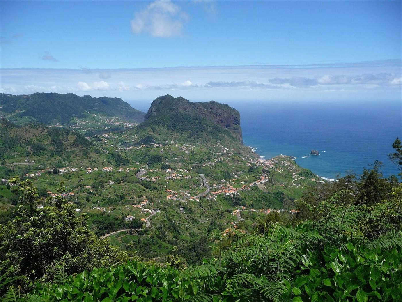 Penha d'Águia rising above Porto da Cruz on Madeira's north coast, the village and its terraced valley below and the Atlantic beyond