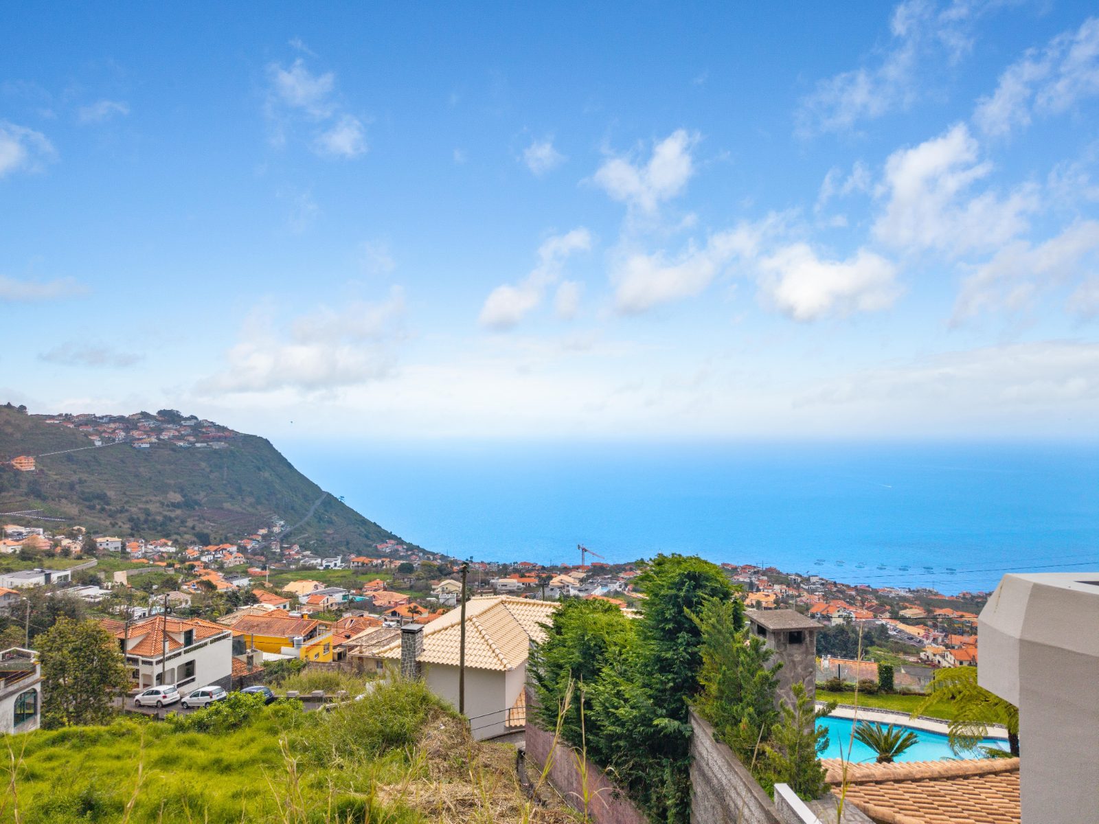 Aerial view toward the coast from above the plot, with a neighbouring pool visible below