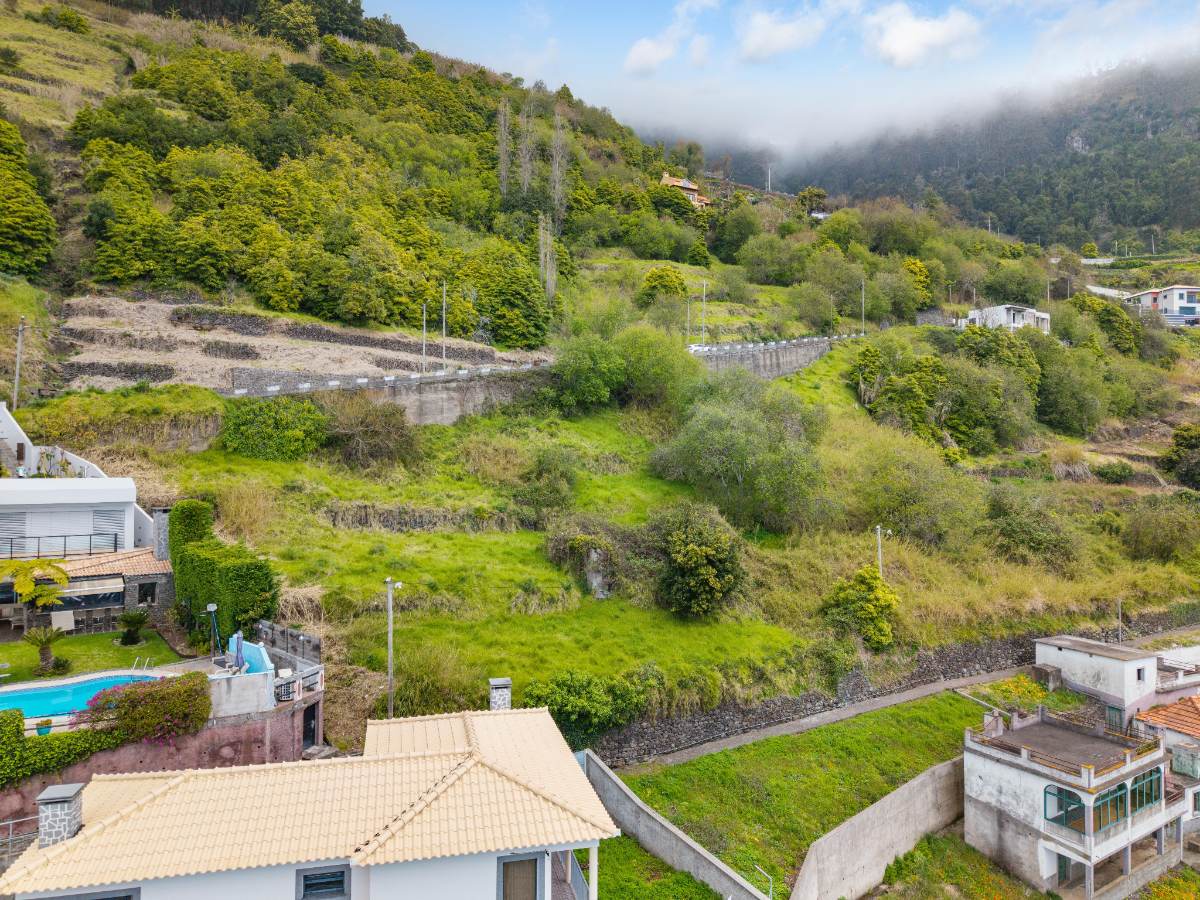 Aerial view of the hillside above the plot, showing terraced ground, a lane, and low cloud over the mountains behind