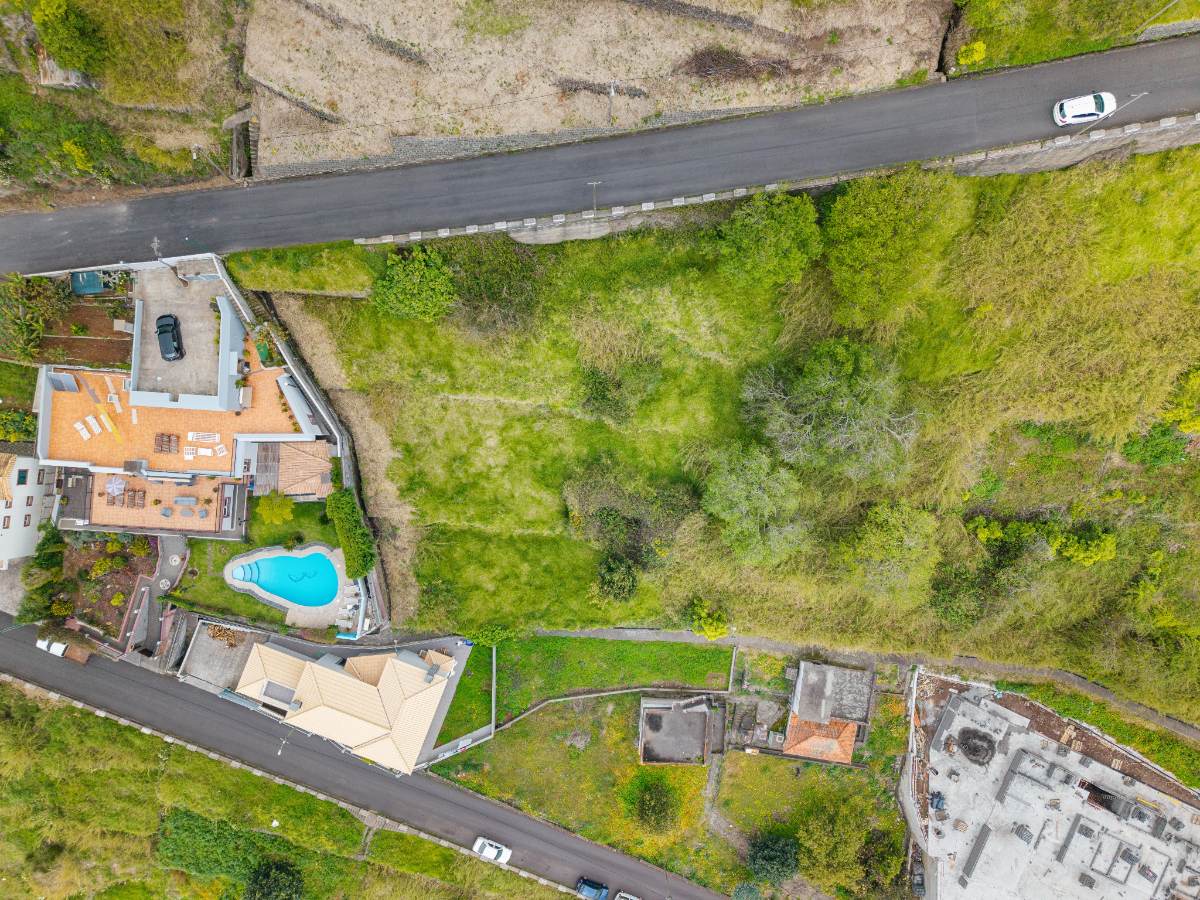 Overhead drone view of the plot boundary beside a neighbouring house under construction and a swimming pool