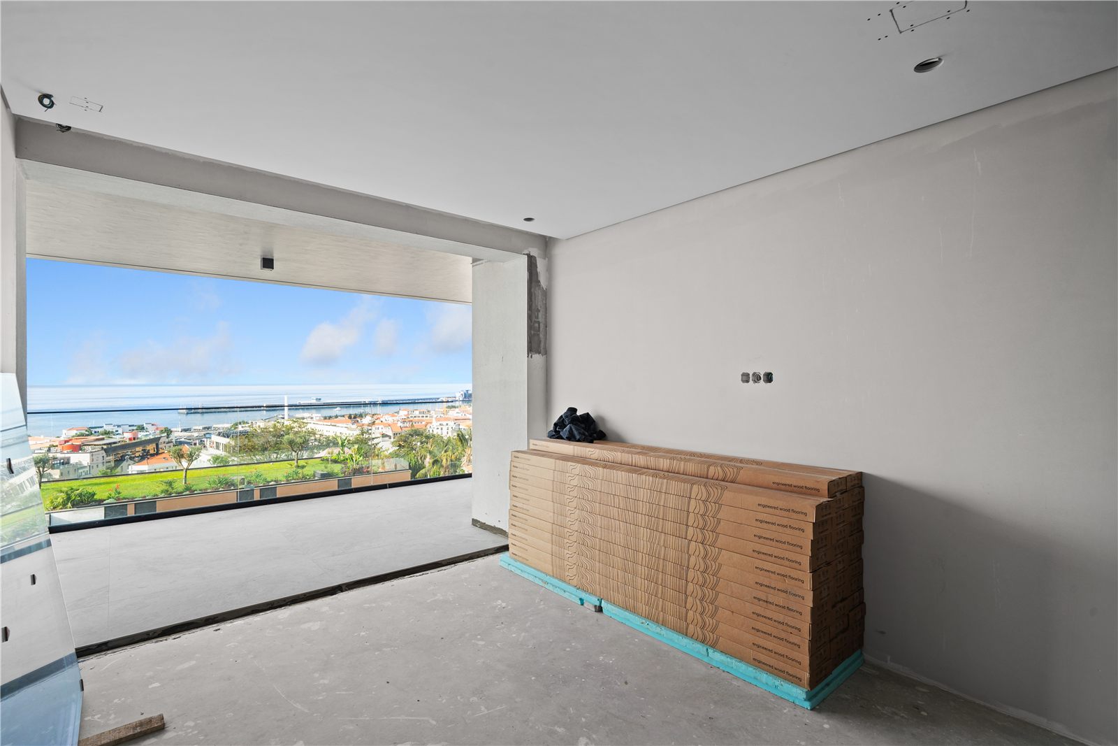A bedroom-sized room with a window over the gardens, packaging and a rattan unit on the bare floor