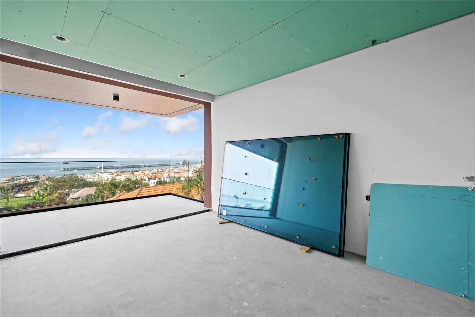A room with a green plasterboard partition still in place and a wide view over the city