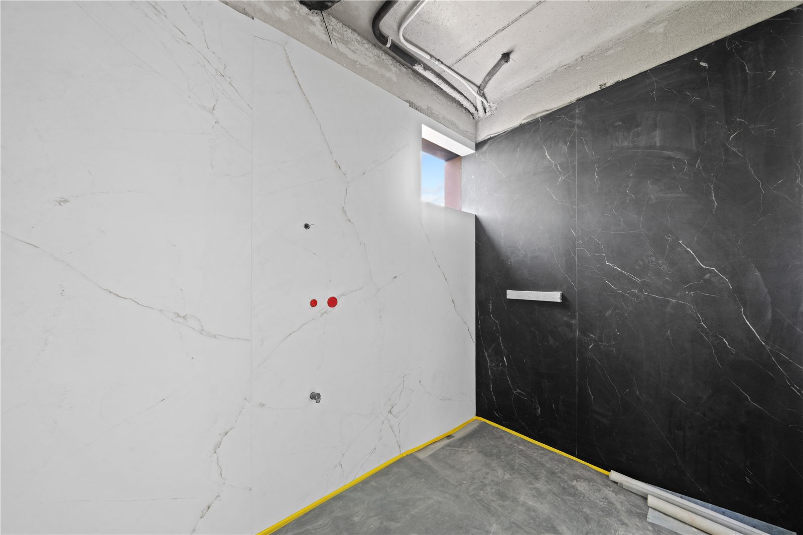 A bathroom lined in dark veined marble, part fitted