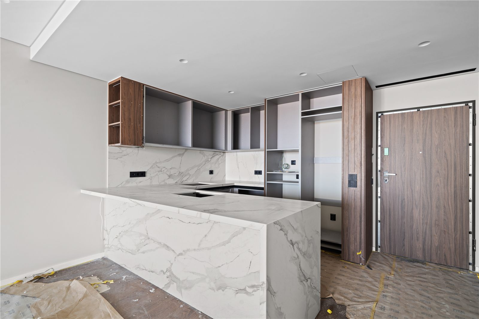 A finished kitchen in the development, marble island and full-height walnut units beside a timber door