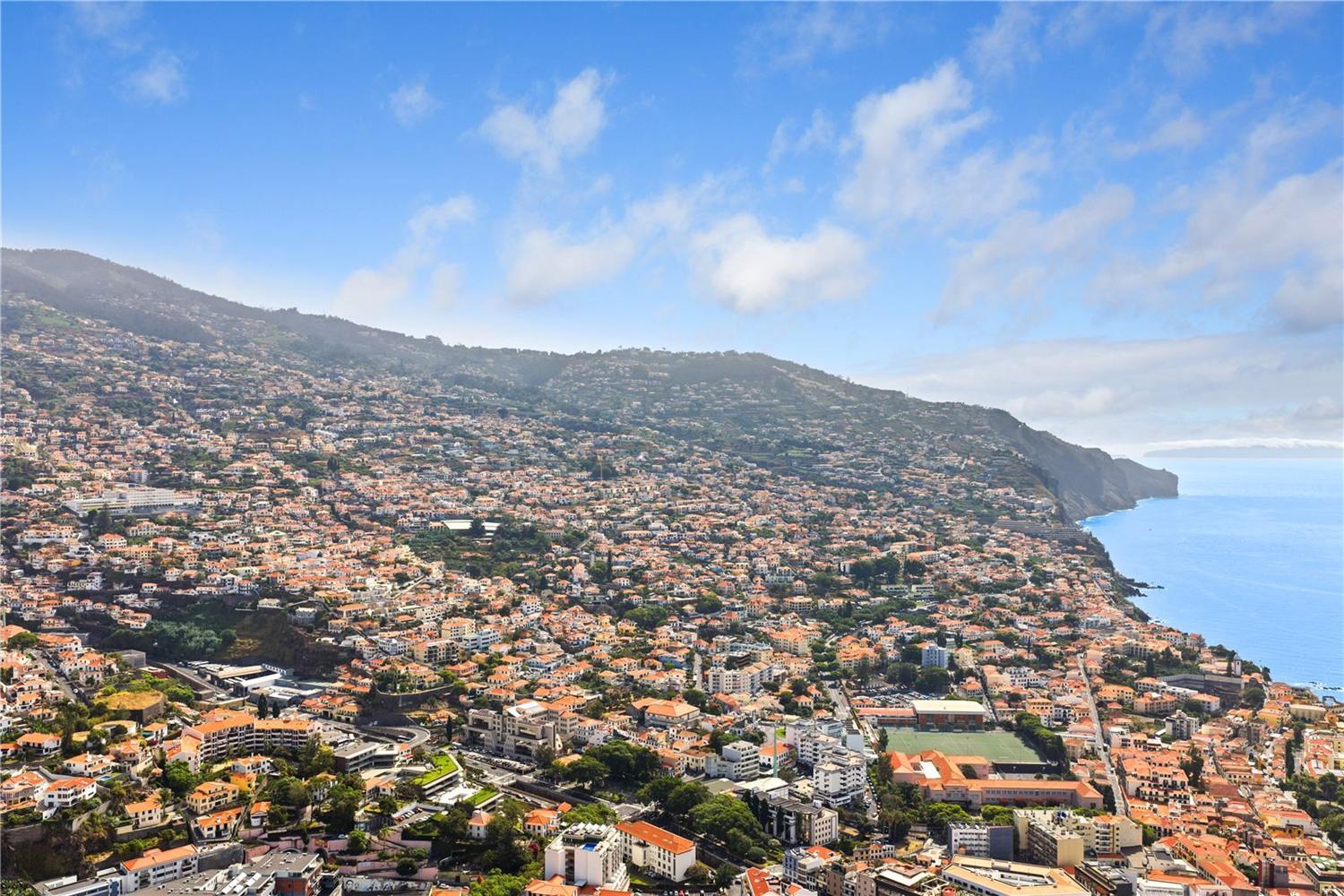 Aerial view over Funchal from above the development, rooftops running down to the sea