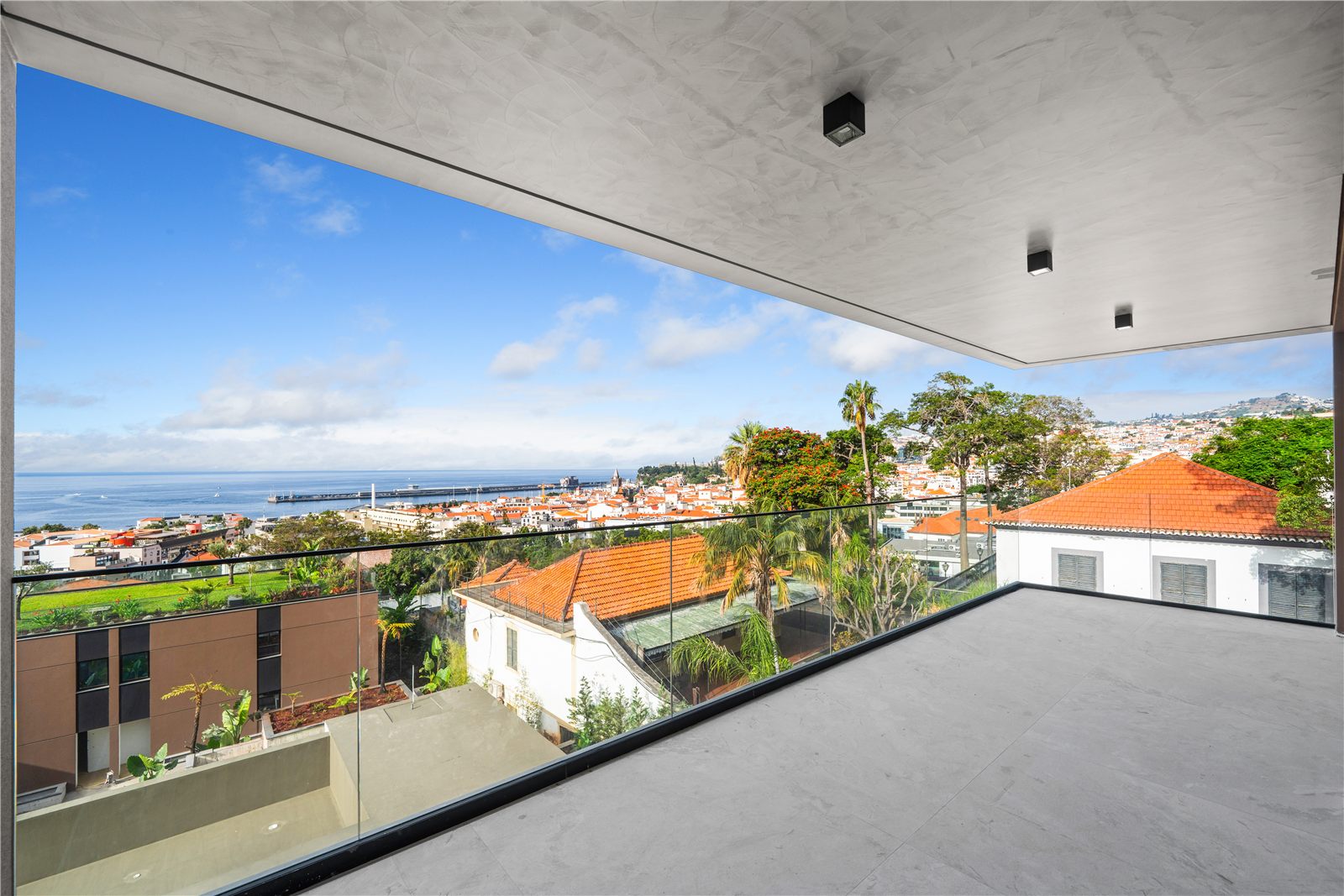 The view from the apartment balcony over neighbouring rooftops and palms to Funchal and the sea