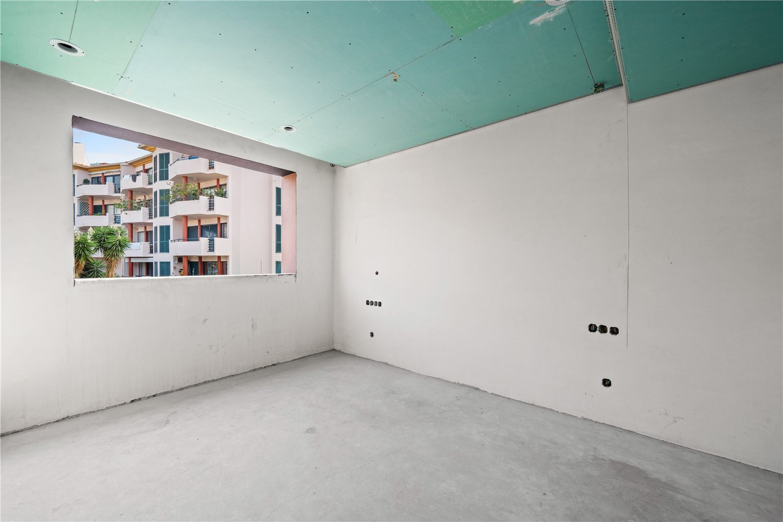 An unfinished room with a window looking across to the next block