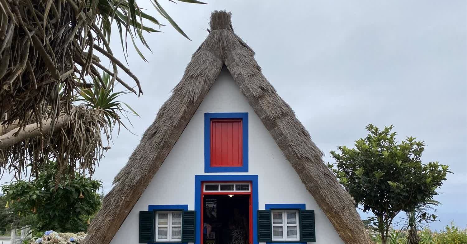 Traditional triangular thatched Casa de Santana house with red and blue trim in Santana, Madeira