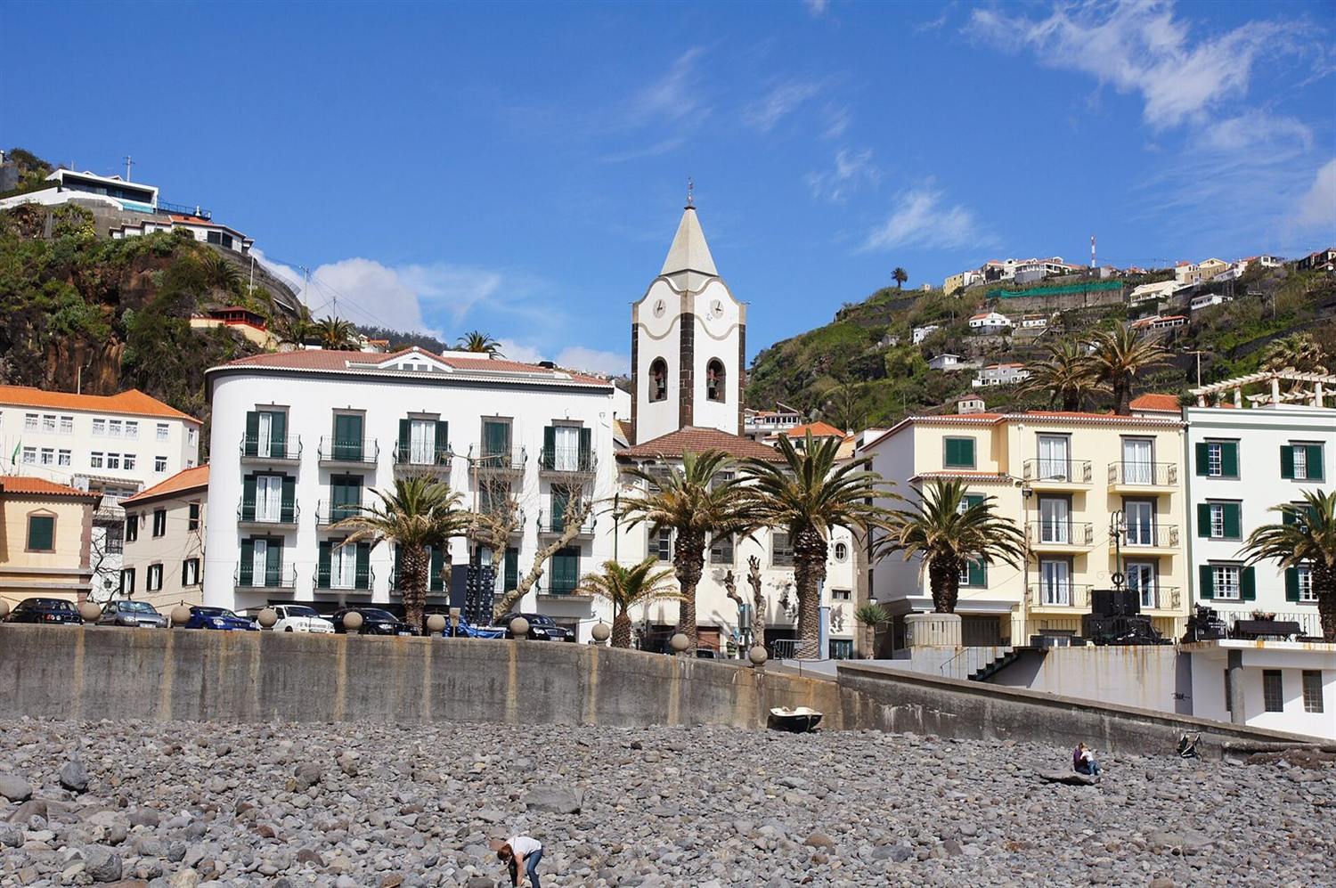 Ponta do Sol, Madeira, with its clock tower and terraced hillside seen from the pebble beach