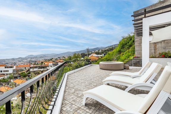 Sun loungers on the paved terrace with rooftops and the sea below