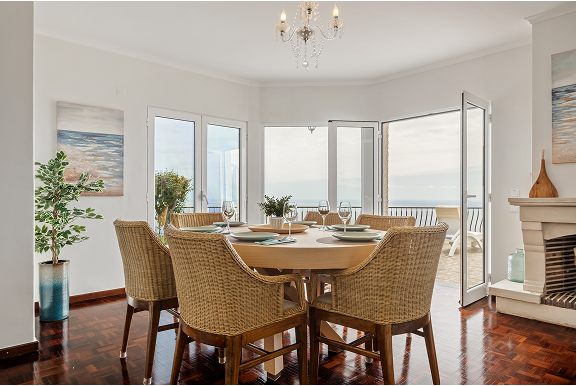 Round dining table by the windows with the sea behind