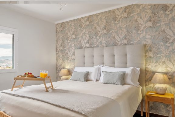 Bedroom with a padded headboard against a patterned wall and a breakfast tray on the bed