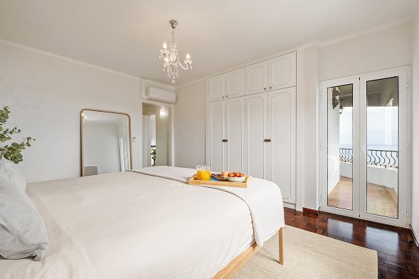 White bedroom with a tall mirror and fitted wardrobes