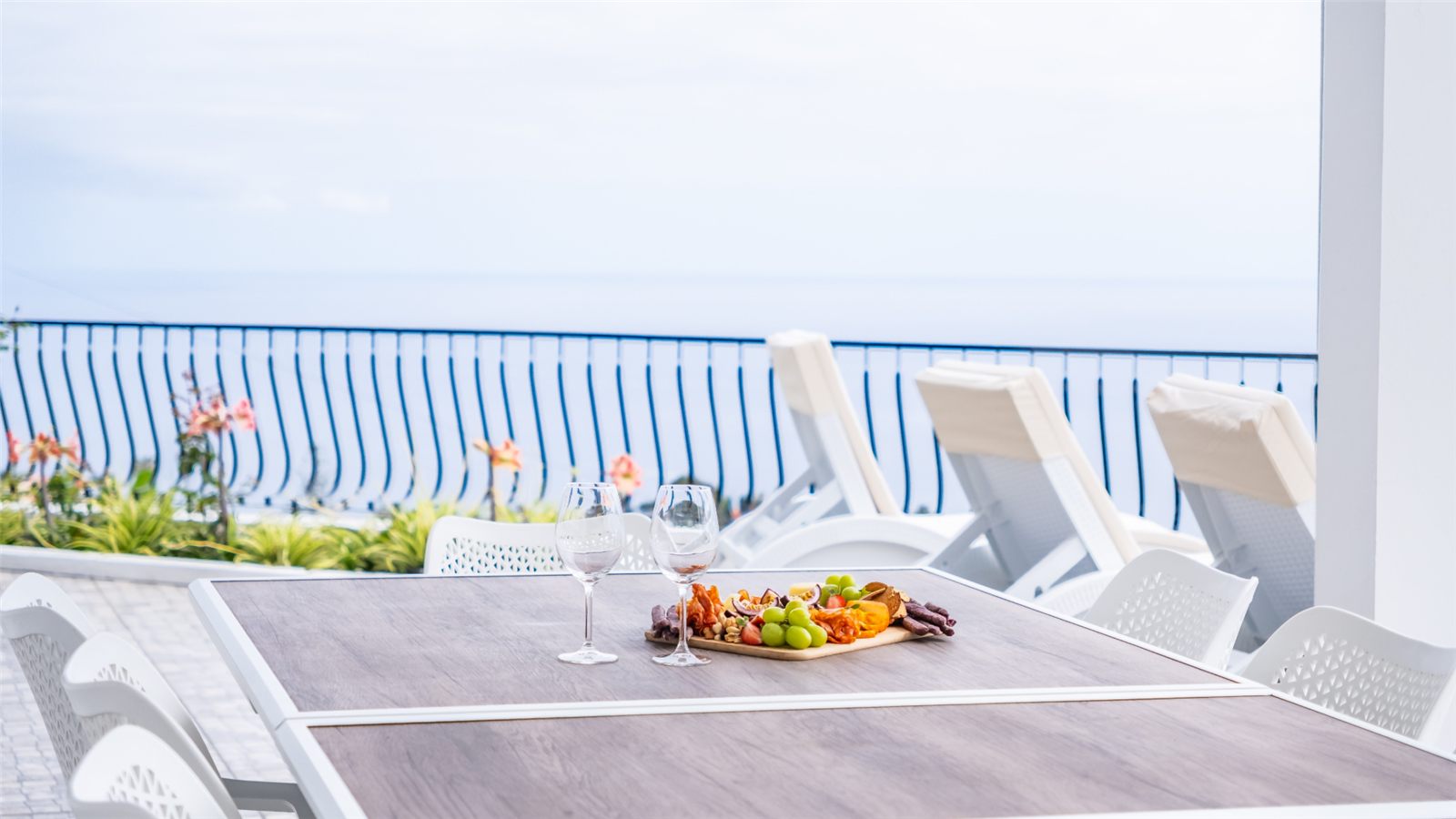 A laid table on the terrace with a grazing board and the bay behind